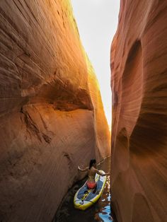 a man riding on top of a kayak through a narrow canyon