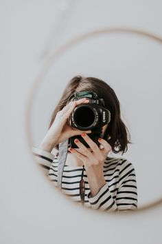 a woman taking a selfie with her camera in front of a circular mirror on the wall