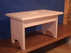 a white wooden bench sitting on top of a hard wood floor next to a blue wall