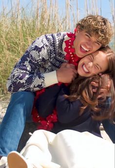 two people sitting on the ground with their arms around each other and smiling at the camera