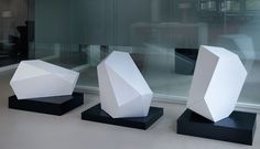 three white sculptures sitting on top of black bases