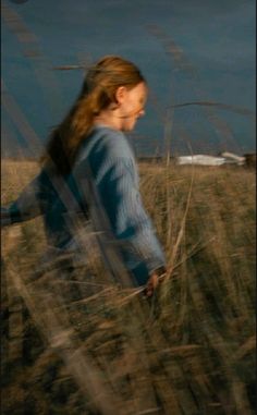 a blurry photo of a woman walking through tall grass