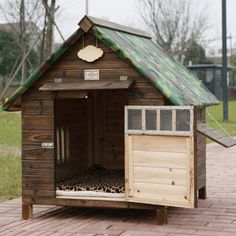 a dog house made out of wood with a green roof and door on the outside