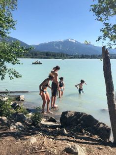 some people are standing in the water near rocks