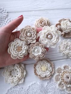 crocheted flowers are being held by someone's hand on a white table