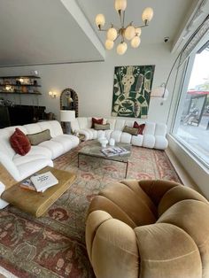 a living room filled with white couches and lots of pillows on top of a rug