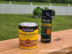 two cans of wood finish sitting on top of a wooden deck next to a can of paint