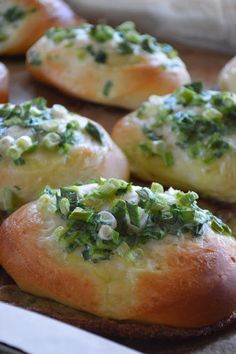 several breads with cheese and spinach on them sitting on a table next to a knife