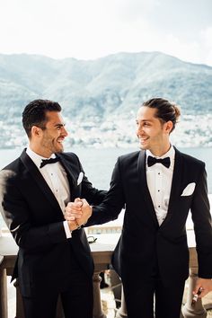 two men in tuxedos standing next to each other and smiling at each other