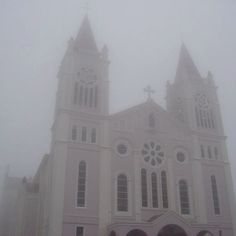 a large white church with two towers on a foggy day