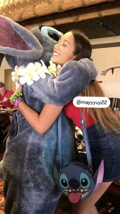 a woman hugging a large stuffed animal with flowers in her lap and smiling at the camera