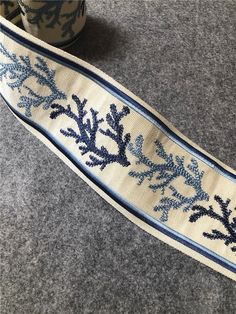 a blue and white ribbon with corals on it next to a cup of coffee