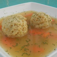 two dumplings are sitting on top of soup in a white bowl with green sprinkles