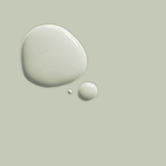 a drop of white paint next to an empty round object on a gray background with one drop in the middle