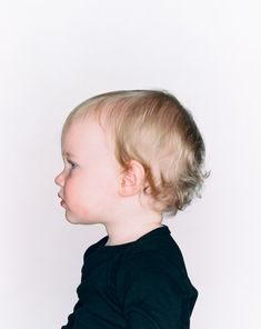 a little boy that is looking at something in the air with his head tilted to the side