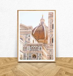 a framed photograph of the dome of an old building in italy, on a wooden table