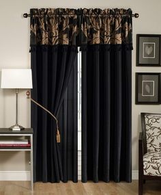 the black curtains are hanging on the wall in front of the chair and table with a lamp