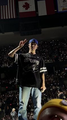 a young man standing on top of a stage in front of an audience at a sporting event