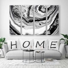 three black and white paintings hanging in a living room