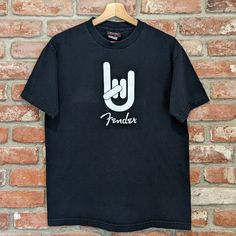 a black t - shirt hanging on a brick wall with the word fenderex printed on it