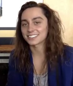 a woman with long hair sitting in front of a computer monitor and smiling at the camera