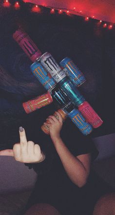 a woman sitting on the floor with her fingers up in front of a stack of cans