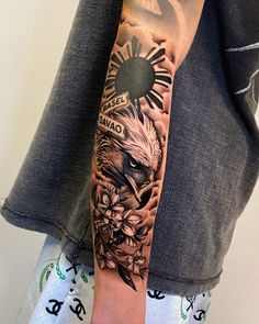 a man's arm with an eagle and flowers tattoo on the left side of his arm