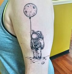 a man with a tattoo on his arm holding a balloon in the shape of an astronaut's head