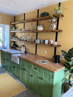 a kitchen with green cabinets and shelves filled with dishes