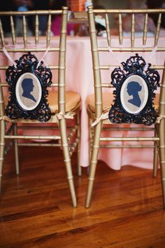 two chairs with pictures on them sitting in front of a pink table cloth covered table