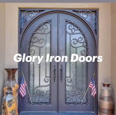 an iron door with american flags and vases on the side walk in front of it