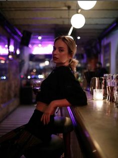 a woman sitting at a bar with her arms crossed and looking off to the side