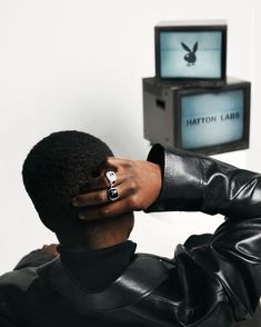 a man with his hand on his head in front of a television and an eagle ring