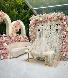 a white couch sitting next to a flower covered wall with pink and white flowers on it