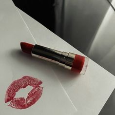 a red lipstick is laying on top of a piece of paper