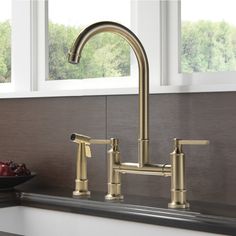 a kitchen sink with a faucet and bowl of fruit on the counter