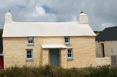 a small yellow house with blue shutters on the front and side windows is shown