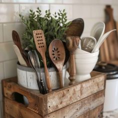 wooden utensils and spoons sit in a container on a counter top next to a potted plant