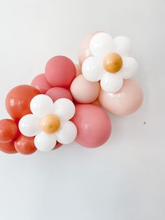 some balloons are arranged in the shape of flowers on a white background with orange and pink colors