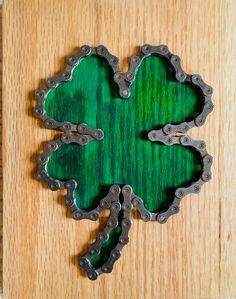 a shamrock made out of chains on top of a wooden surface with the shape of a four leaf clover