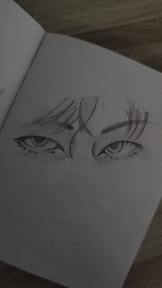 an open book with a drawing of eyes on the page and one eye drawn in pencil