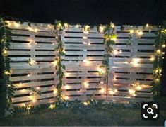 a wooden fence covered in lights and greenery