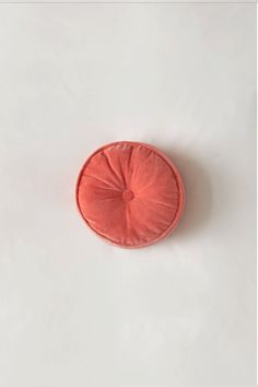 an orange round cushion sitting on top of a white surface