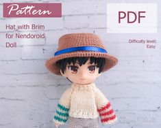 the doll is wearing a knitted hat and striped scarf, while standing next to a brick wall