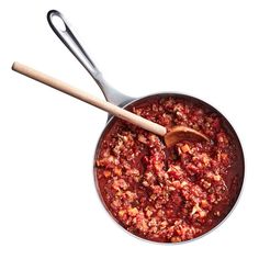 a pan filled with food and a wooden spoon in it's side, on a white background