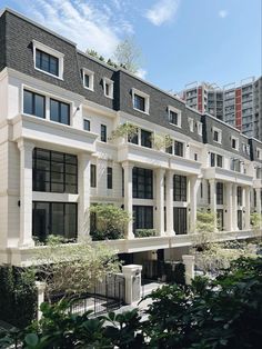 an apartment building with many windows and balconies on the top floor, surrounded by greenery