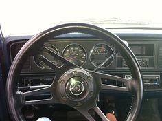 the steering wheel and dashboard of a car with gauges on it's dash board