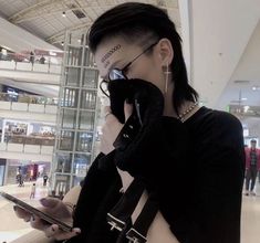 a woman with tattoos on her face holding a cell phone and looking at the screen