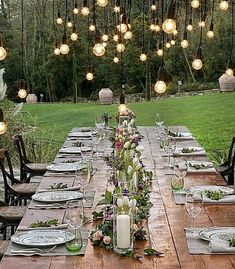 a long wooden table set with plates and place settings for an outdoor dinner in the woods