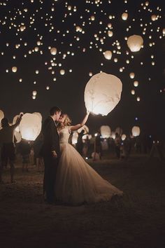 a bride and groom are holding lanterns in the air as they fly through the night sky